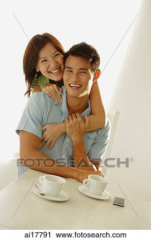 Woman embracing man from behind, both smiling at camera View Large Photo Image Stock Image - Woman embracing man from behind, both smiling at camera . Fotosearch