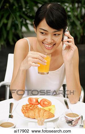 Woman having breakfast, using mobile phone View Large Photo Image Stock Image - Woman having breakfast, using mobile phone. Fotosearch