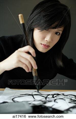 Woman holding Chinese paintbrush, painting Chinese calligraphy View Large Photo Image Stock Photograph - Woman holding Chinese paintbrush, painting Chinese calligraphy . Fotosearch