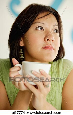 Woman holding cup, looking away View Large Photo Image Picture - Woman holding cup, looking away. Fotosearch