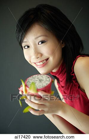 Woman holding cut dragon fruit, smiling at camera View Large Photo Image Stock Image - Woman holding cut dragon fruit, smiling at camera . Fotosearch
