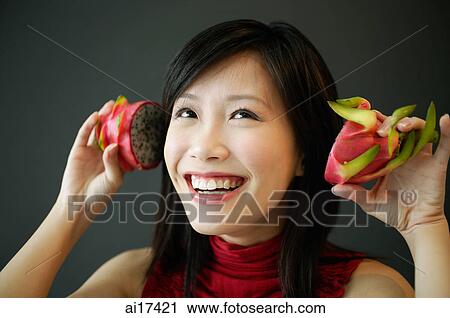 Woman holding dragon fruit halves next to her ears, smiling View Large Photo Image Stock Image - Woman holding dragon fruit halves next to her ears, smiling . Fotosearch