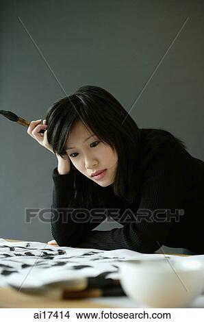 Woman holding paintbrush, leaning head on hand View Large Photo Image Picture - Woman holding paintbrush, leaning head on hand . Fotosearch
