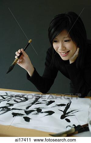 Woman holding paintbrush, looking at Chinese script on paper View Large Photo Image Stock Image - Woman holding paintbrush, looking at Chinese script on paper . Fotosearch
