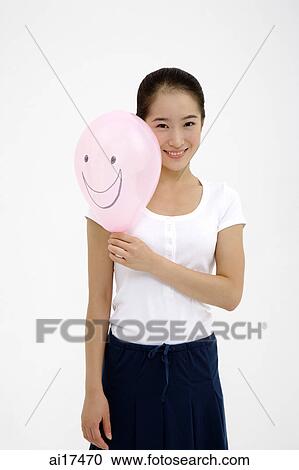 Stock Image - Woman holding pink balloon, smiling . Fotosearch