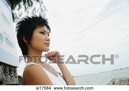 Woman in sleeveless top, standing by sea, looking away View Large Photo Image Picture - Woman in sleeveless top, standing by sea, looking away. Fotosearch