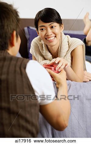 Woman lying on bed, man passing woman a box View Large Photo Image Stock Photograph - Woman lying on bed, man passing woman a box. Fotosearch