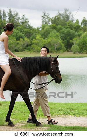 Woman on horse, man walking beside her View Large Photo Image Stock Image - Woman on horse, man walking beside her . Fotosearch