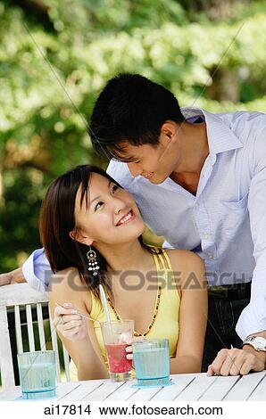 Woman sitting at table, man next to her leaning down View Large Photo Image Picture - Woman sitting at table, man next to her leaning down . Fotosearch