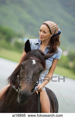 Stock Photograph - Woman sitting on horse, looking away . Fotosearch