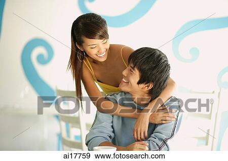 Woman standing behind seated man, embracing him from behind View Large Photo Image Stock Photo - Woman standing behind seated man, embracing him from behind . Fotosearch