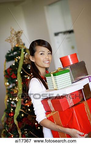 Stock Photo - Woman standing, carrying a pile of gifts . Fotosearch