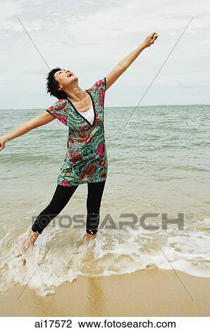 Woman standing in sea, looking up, arms outstretched View Large Photo Image Stock Image - Woman standing in sea, looking up, arms outstretched . Fotosearch