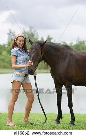 Woman standing with horse, smiling at camera View Large Photo Image Stock Image - Woman standing with horse, smiling at camera . Fotosearch