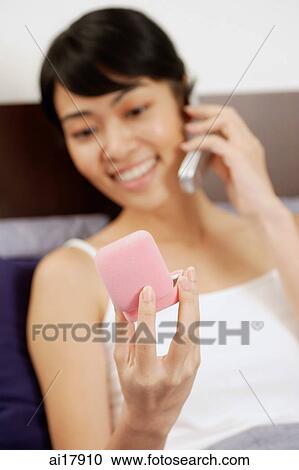 Woman using mobile phone, holding ring box View Large Photo Image Stock Image - Woman using mobile phone, holding ring box . Fotosearch