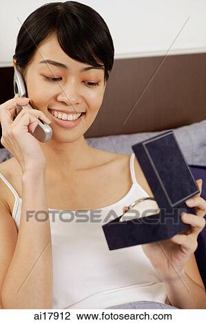 Woman using mobile phone, looking at jewellery box View Large Photo Image Stock Image - Woman using mobile phone, looking at jewellery box. Fotosearch