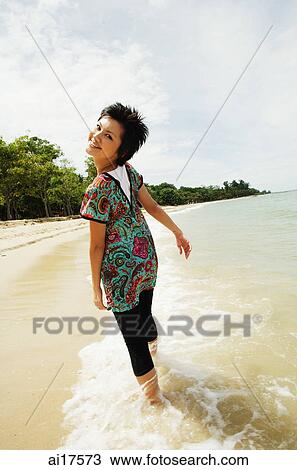 Woman walking on beach, looking over shoulder View Large Photo Image Stock Image - Woman walking on beach, looking over shoulder . Fotosearch