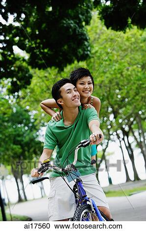 Young couple on tandem bicycle, smiling at camera View Large Photo Image Stock Image - Young couple on tandem bicycle, smiling at camera . Fotosearch