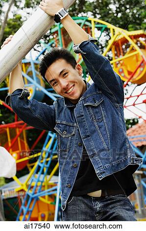 Stock Image - Young man at playground, smiling at camera . Fotosearch