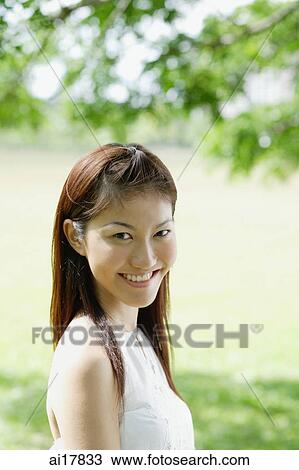 Stock Image - Young woman looking at camera, smiling. Fotosearch