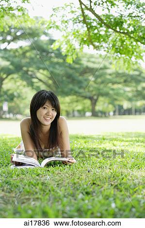 Stock Photograph - Young woman lying on grass, smiling at camera . Fotosearch
