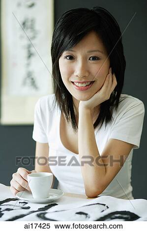 Young woman with teacup and saucer, smiling, hand on chin View Large Photo Image Stock Photography - Young woman with teacup and saucer, smiling, hand on chin . Fotosearch