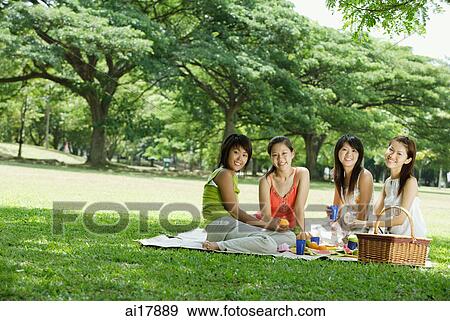 Stock Photo - Young women having picnic, smiling at camera . Fotosearch