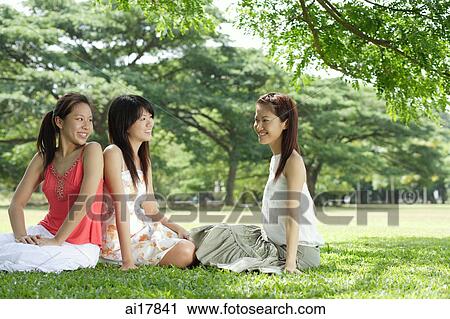 Young women in park, sitting on grass View Large Photo Image Stock Image - Young women in park, sitting on grass. Fotosearch