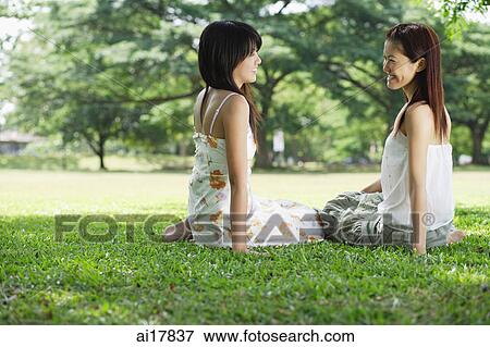 Young women in park, sitting on grass View Large Photo Image Stock Photo - Young women in park, sitting on grass . Fotosearch