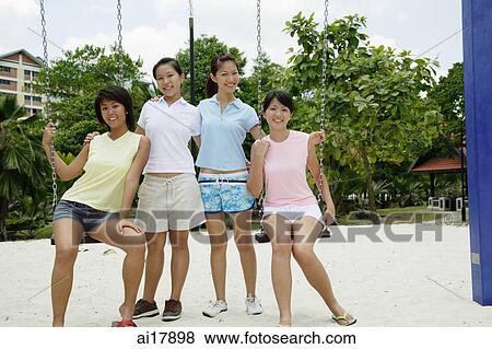 Young women in playground, sitting on swings, smiling at camera View Large Photo Image Stock Photo - Young women in playground, sitting on swings, smiling at camera . Fotosearch