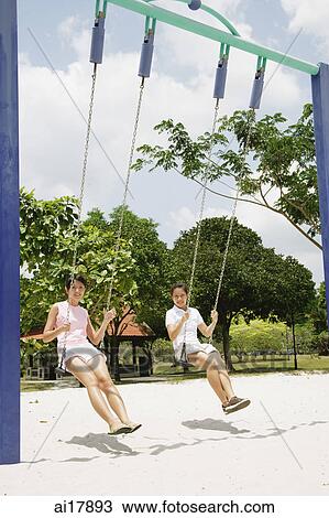 Young women on swings at playground View Large Photo Image Stock Image - Young women on swings at playground . Fotosearch