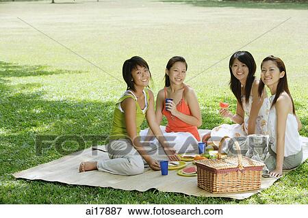 Young women sitting in park, having picnic, smiling at camera View Large Photo Image Stock Photo - Young women sitting in park, having picnic, smiling at camera . Fotosearch