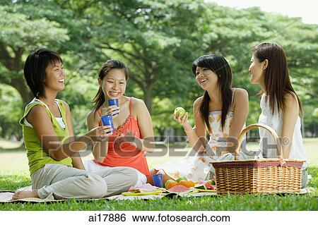 Young women sitting in park, having picnic View Large Photo Image Stock Photograph - Young women sitting in park, having picnic . Fotosearch