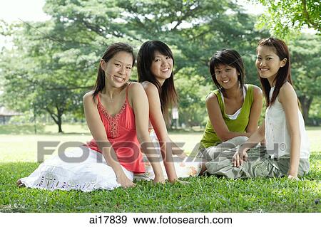 Young women sitting in park, smiling at camera View Large Photo Image Stock Photo - Young women sitting in park, smiling at camera . Fotosearch