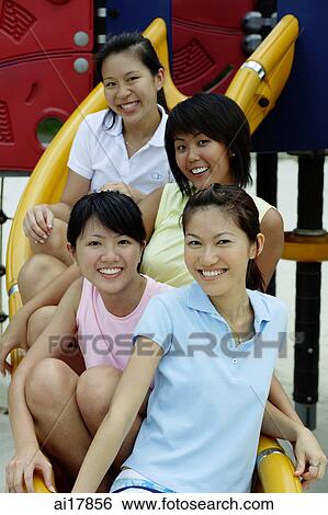 Young women sitting on slide in playground, smiling at camera View Large Photo Image Stock Photograph - Young women sitting on slide in playground, smiling at camera . Fotosearch