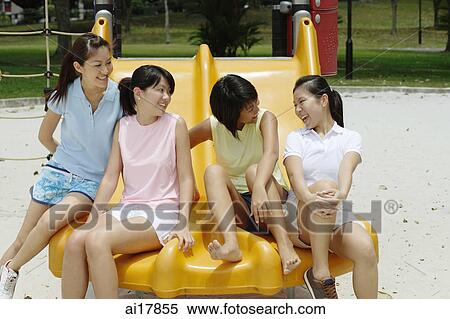 Young women sitting on slide in playground, talking View Large Photo Image Stock Photography - Young women sitting on slide in playground, talking. Fotosearch