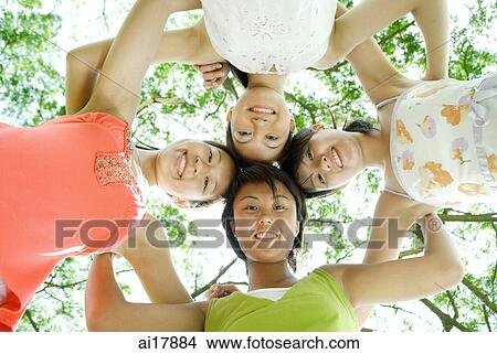 Young women standing side by side, looking down at camera View Large Photo Image Picture - Young women standing side by side, looking down at camera . Fotosearch