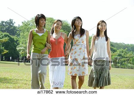 Young women walking side by side in park View Large Photo Image Stock Image - Young women walking side by side in park. Fotosearch
