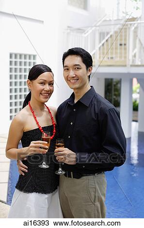 Stock Image - Couple by poolside, holding champagne glasses . Fotosearch