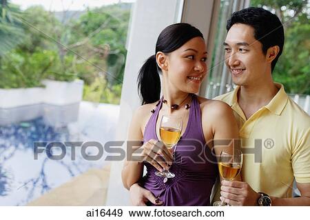 Couple holding wine glasses, looking at each other View Large Photo Image Stock Photo - Couple holding wine glasses, looking at each other . Fotosearch