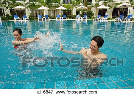 Couple in swimming pool, having water fight View Large Photo Image Stock Photo - Couple in swimming pool, having water fight . Fotosearch
