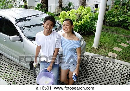 Couple leaning against car, smiling at camera View Large Photo Image Stock Image - Couple leaning against car, smiling at camera . Fotosearch