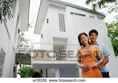 Stock Photography - Couple looking at camera, house behind them . Fotosearch