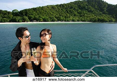 Couple on boat deck, standing next to railing, toasting champagne glasses View Large Photo Image Stock Photo - Couple on boat deck, standing next to railing, toasting champagne glasses . Fotosearch