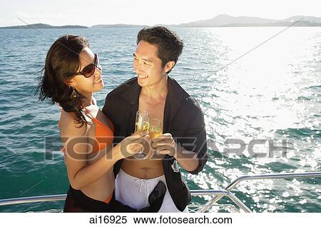 Couple on boat, holding champagne glasses, toasting View Large Photo Image Stock Photography - Couple on boat, holding champagne glasses, toasting. Fotosearch