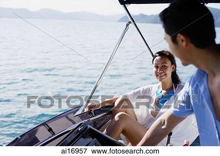Couple on yacht, man at helm, smiling at woman sitting next to him View Large Photo Image Stock Photo - Couple on yacht, man at helm, smiling at woman sitting next to him. Fotosearch