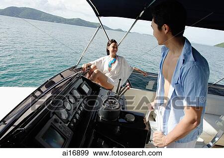 Couple on yacht, man at helm View Large Photo Image Stock Photo - Couple on yacht, man at helm . Fotosearch