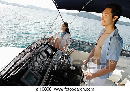 Couple on yacht, man steering, woman sitting, looking away View Large Photo Image Stock Photo - Couple on yacht, man steering, woman sitting, looking away . Fotosearch