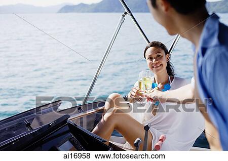 Couple on yacht, toasting with drinks View Large Photo Image Stock Photo - Couple on yacht, toasting with drinks . Fotosearch