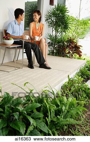 Couple sitting and having coffee on patio View Large Photo Image Stock Image - Couple sitting and having coffee on patio. Fotosearch